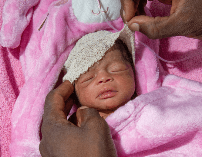 A premature baby wrapped in a pink blanket in Nigeria.