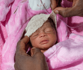 A premature baby wrapped in a pink blanket in Nigeria.